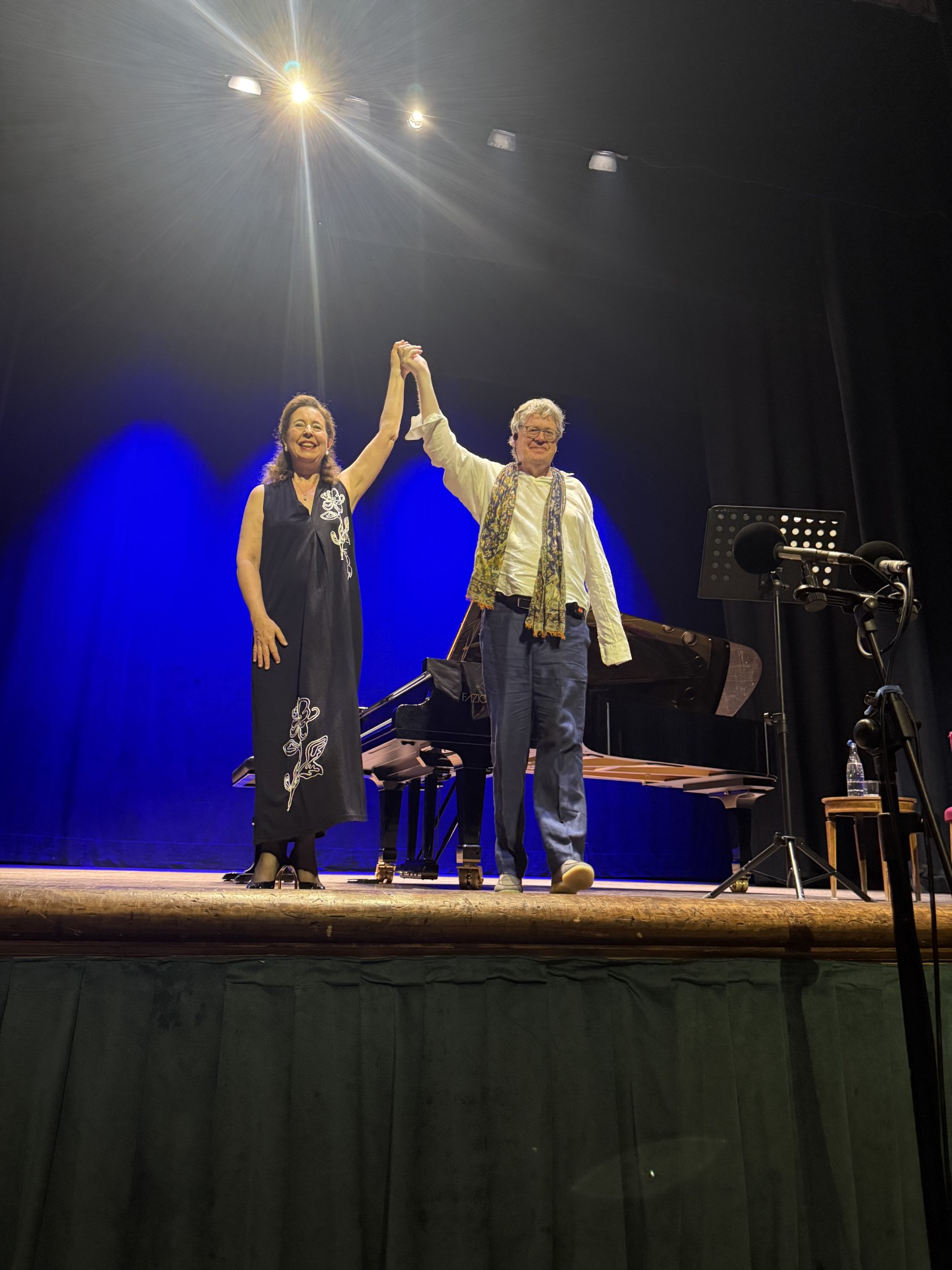 James Runcie taking a bow on stage with pianist Angela Hewitt beside a grand piano